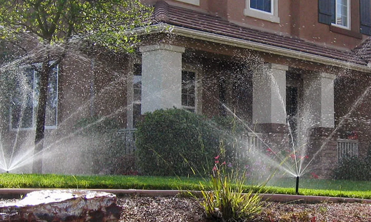 Technician trenching a residential lawn for a new sprinkler zone
