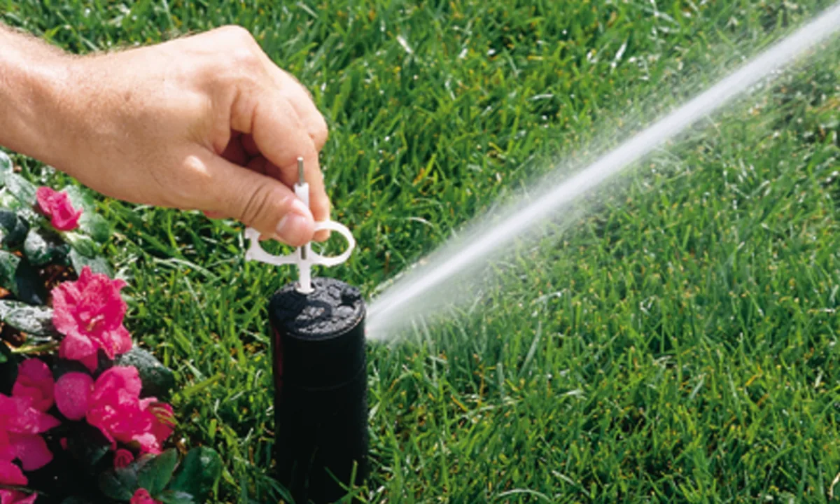 Sprinkler head being repaired by a technician's gloved hand
